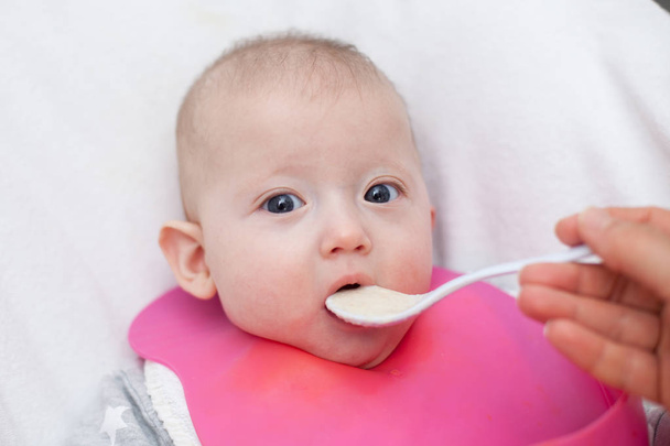 madre da comida de bebé de una cuchara de bebé. bebé comiendo comida por primera vez. bebé destete  - Foto, imagen
