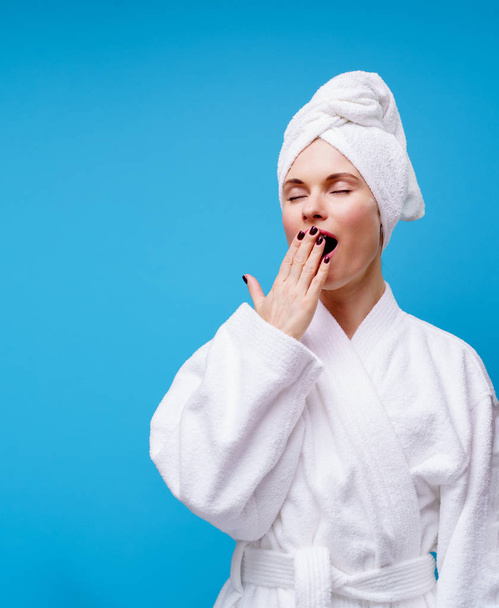 Image of yawning woman in white coat and towel on head - Fotoğraf, Görsel