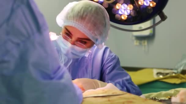 Na sala de operações do hospital. Uma equipe diversificada de cirurgiões profissionais e enfermeiros, uma ferida de sutura após uma operação bem sucedida
 - Filmagem, Vídeo