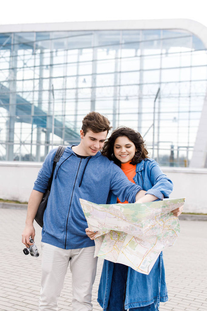 Fiatal aranyos pár - egy fiú és egy lány sétálnak a városban egy térképpel és fényképezőgéppel a kezükben. A fiatalok utaznak. - Fotó, kép