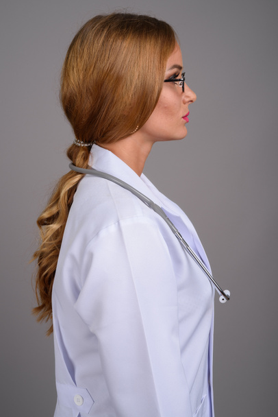 Mladá krásná žena lékař s blond vlasy proti šedé backgr - Fotografie, Obrázek