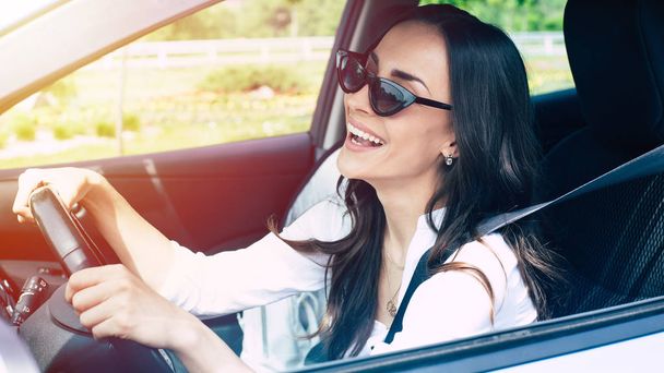 Beautiful female driver in sunglasses driving car - Foto, Bild