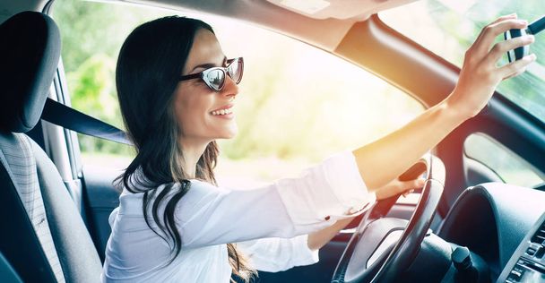 Beautiful female driver adjusting rearview mirror in car - Foto, immagini