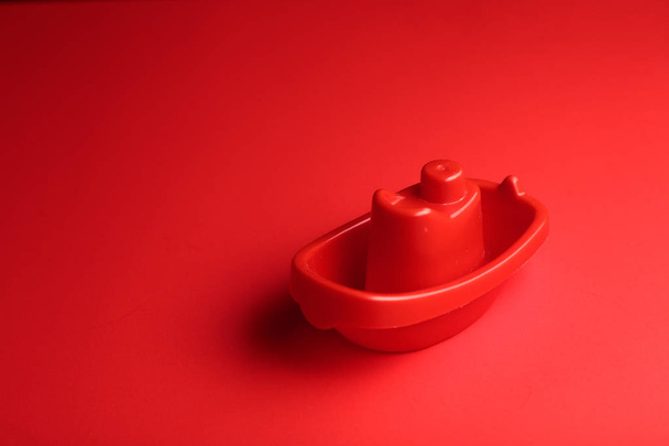 little red plastic toy ship on the red background with copy space. - Fotografie, Obrázek