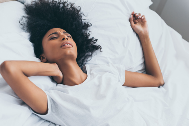 beautiful african american woman suffering from neck pain while lying in bed - Foto, Imagem