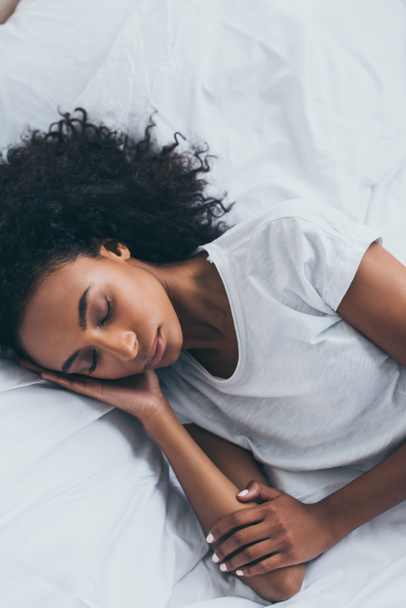 beautiful tired african american woman sleeping on white bedding  - Foto, Imagem