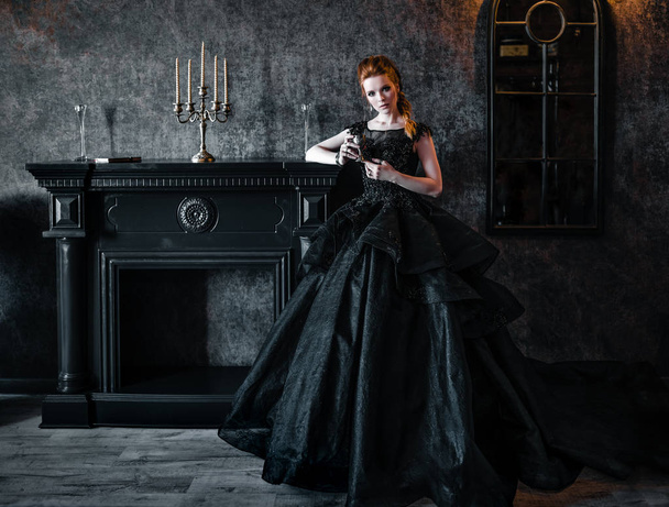 Attractive woman in black dress in medieval interior - Fotografie, Obrázek
