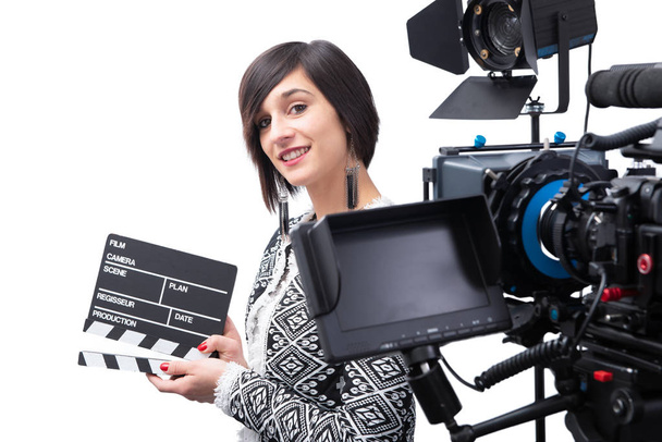 Een jonge vrouw met een klapbord. videocamera, op de witte rug - Foto, afbeelding