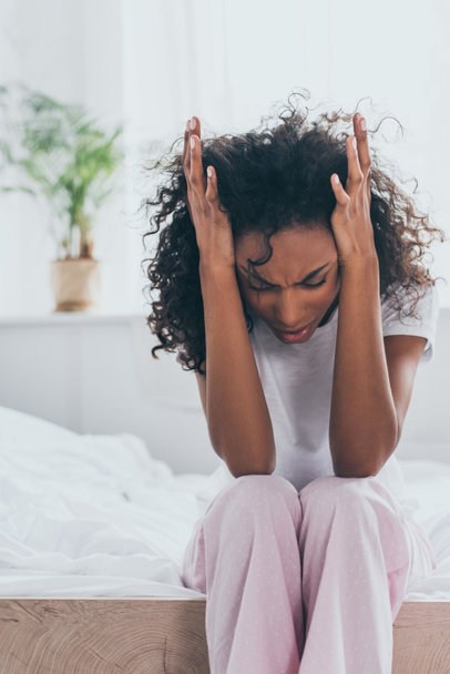 infelice donna afroamericana che si tiene per mano vicino alla testa mentre soffre di mal di testa in camera da letto
 - Foto, immagini