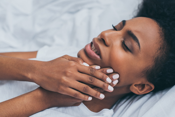 mujer afroamericana bastante que sufre de dolor de muelas mientras está acostada en la cama
 - Foto, Imagen