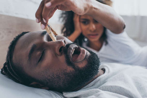 selective focus of snoring african american man near wife holding wooden pin - Photo, Image
