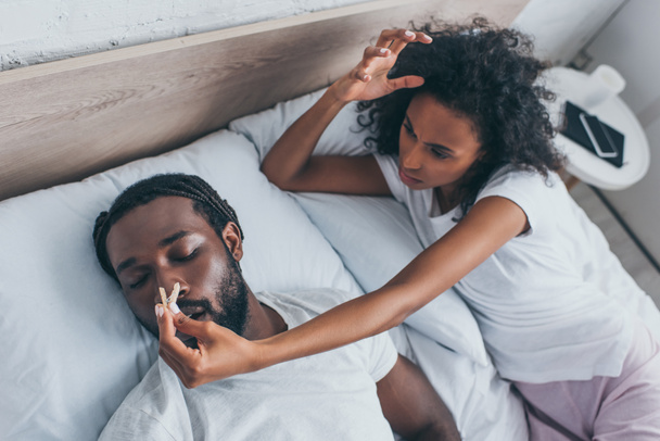 young african american woman pinning nose of snoring husband  - Photo, Image