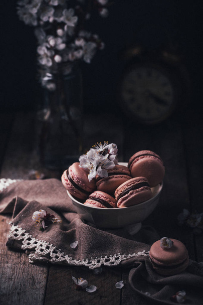 čokoládové makaroony s bílými květy na dřevěné pozadí  - Fotografie, Obrázek