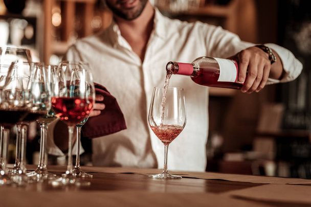 Professional young bartender pouring down pink champagne - Foto, Imagen
