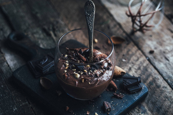 chocolate mousse in glass with spoon on wooden background - 写真・画像