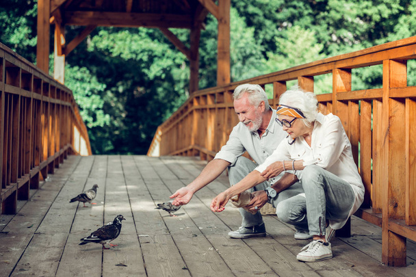 Contended couple feeding up the pigeons on the bridge - Foto, imagen