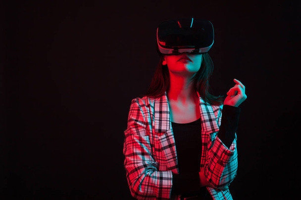 Portrait of beautiful teengage girl wearing modern virtual reality helmet with color gels - Photo, Image
