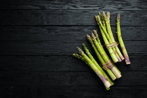 Green asparagus. Fresh asparagus on a black background. Top view. Free space for your text. - Foto, immagini