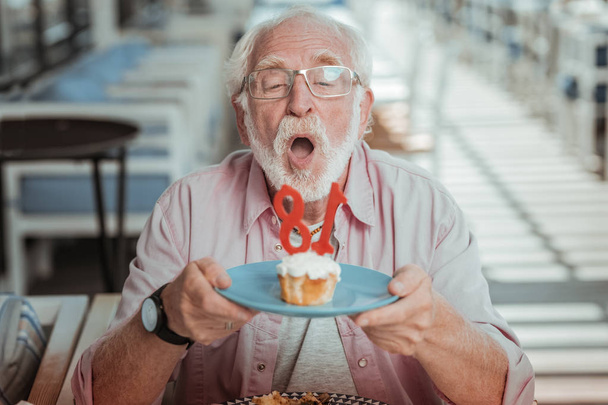 Handsome elderly man staring at candle on the cake - Foto, Bild