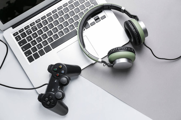 Ordenador portátil, almohadilla de juego y auriculares sobre fondo gris
 - Foto, Imagen