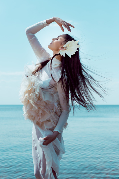 beyaz kuğu kostümlü genç kadının yan görünümü jest yapma, gözlerini kapatan - Fotoğraf, Görsel