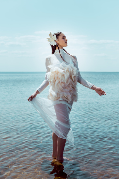 dreamy and elegant woman in white swan costume standing on river backgrond - Foto, afbeelding