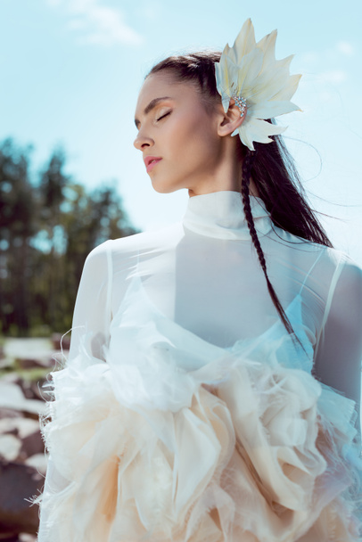 low angle view of tender woman in white swan costume standing on forest and beach background - Fotografie, Obrázek
