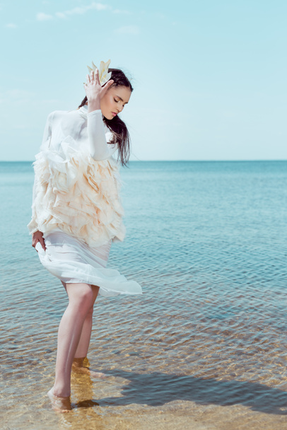 beautiful woman in white swan costume standing on sand bottom - Foto, Bild