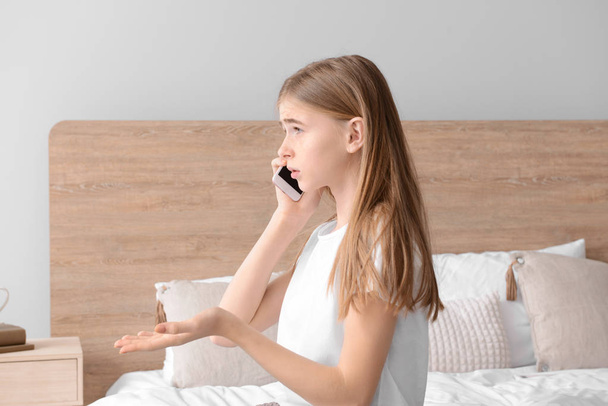 Cute teenage girl talking by mobile phone in bedroom at home - Fotoğraf, Görsel