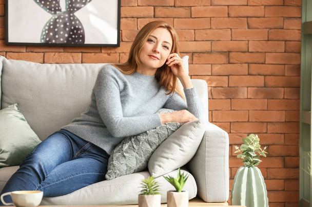 Portrait of mature woman resting on sofa at home - Photo, Image