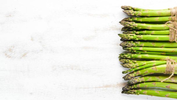 Fresh green asparagus on a white wooden background. Healthy food. Top view. Free space for your text. - Photo, image