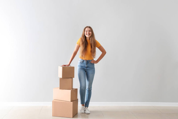 Young woman with cardboard boxes near light wall - Photo, Image