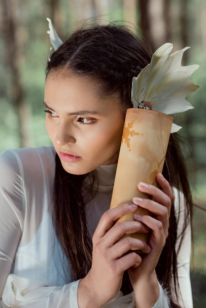 retrato de jovem mulher em traje de cisne branco segurando rolagem, olhando para longe
 - Foto, Imagem