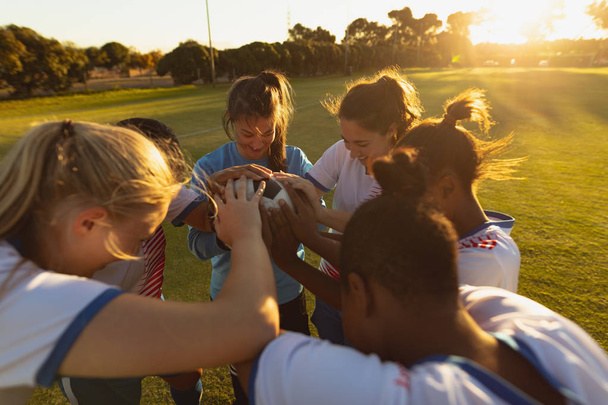 Korkea kulma näkymä monipuolinen naisten jalkapallojoukkue hurraavat ympyrän kanssa pallo urheilukentällä
 - Valokuva, kuva