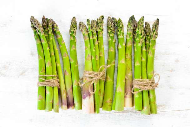 Fresh green asparagus on a white wooden background. Healthy food. Top view. Free space for your text. - Foto, imagen