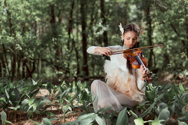 beautiful woman in white swan costume playing on violin - 写真・画像