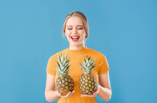 Beautiful young woman with pineapples on color background - Photo, Image