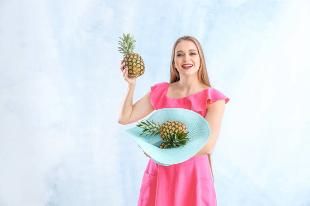 Beautiful young woman with pineapples on color background - Foto, afbeelding
