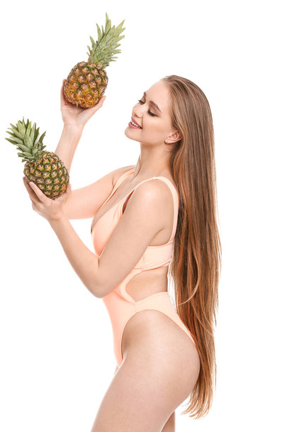 水着と白い背景にパイナップルを持つ美しい若い女性 - 写真・画像