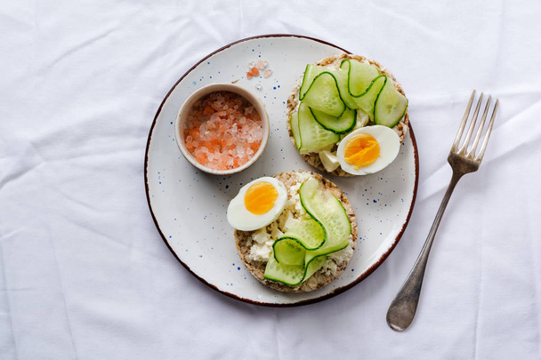 Sandwich with boiled egg and cucumber on ceramic plate on gray old background. Top view. - Foto, Bild