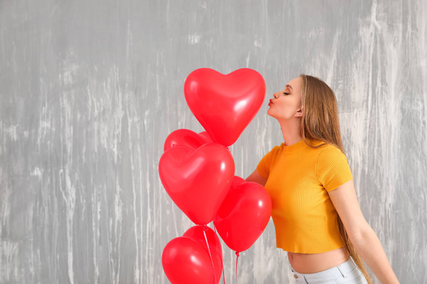Belle jeune femme avec des ballons à air en forme de coeur contre le mur de grunge
 - Photo, image