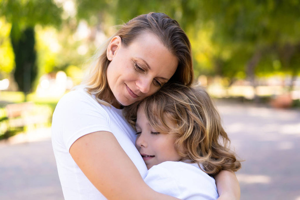 公園で抱き合い、抱きしめる母と息子 - 写真・画像