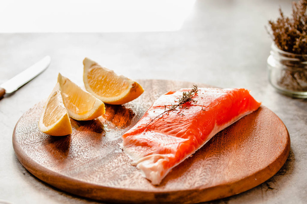Raw salmon fish filet with lemon and spices. On a wooden backgro - Fotografie, Obrázek
