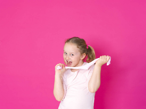 beautiful blonde little girl playing with slime in front of pink background - Fotoğraf, Görsel