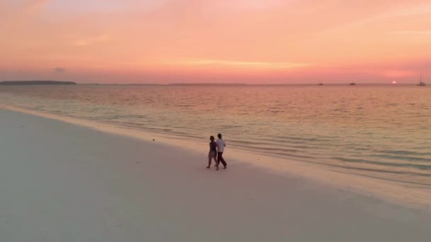 Pareja de vacaciones caminando en la playa exótica con el cielo romántico dramático al atardecer Islas Pasir Panjang Kei Indonesia Molucas Maluku Indonesia, viajar personas pareja concepto de relación
 - Metraje, vídeo