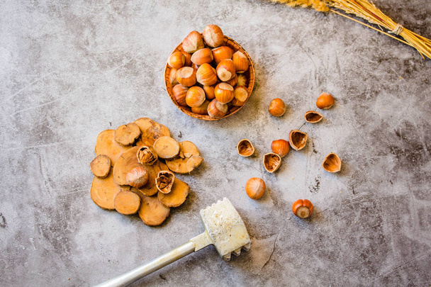 Hazelnuts in the shell in a small bowl and nutcracker. On a gray - Valokuva, kuva
