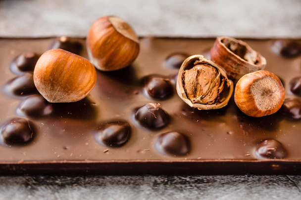 Dark chocolate with hazelnuts in the shel on gray backgroundl, c - Fotó, kép