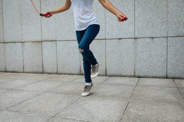 Young fitness woman with skipping rope against city wall - Foto, immagini