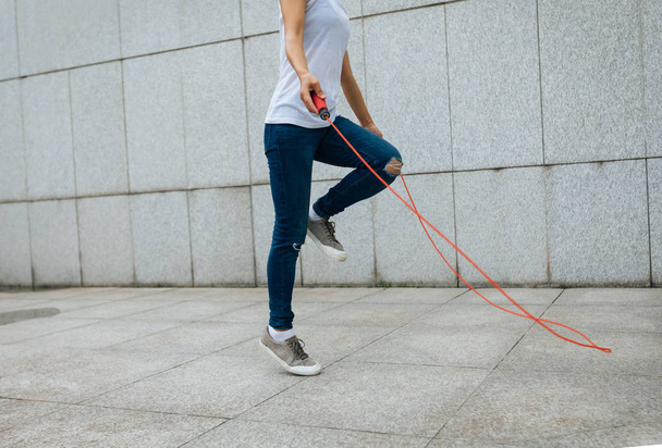 Young fitness woman with skipping rope against city wall - Foto, Bild