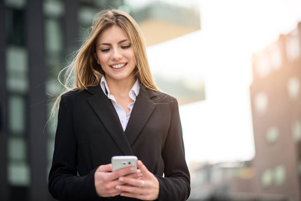 Smiling businesswoman using her mobile phone - Фото, изображение